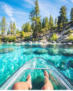 a person's feet on the edge of a boat as it floats through clear blue water