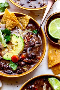 three bowls filled with black bean chili and tortilla chips