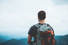 a man standing on top of a mountain with a backpack