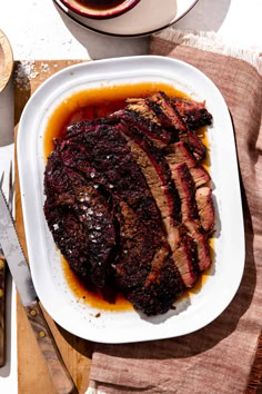 a large piece of meat sitting on top of a white plate next to a cup of coffee