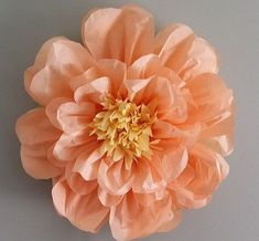 a large pink flower sitting on top of a white table next to a gray wall