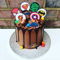 a birthday cake decorated with superheros and other edible items on a white tablecloth