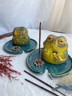 there are two decorative items sitting on the table with feathers and twigs in front of them