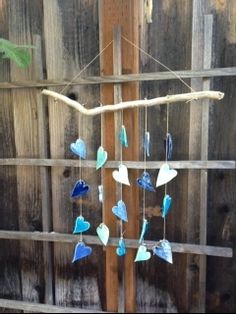 a wind chime hanging from a wooden fence with blue and green glass pieces on it