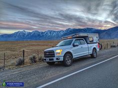 the truck is parked on the side of the road in front of the mountain range