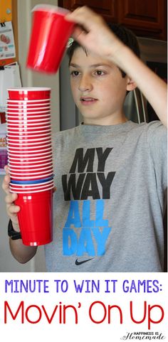 a young boy holding up a stack of red cups