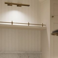 a kitchen with white cabinets and marble counter tops in front of a wall mounted light