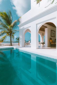 an outdoor swimming pool with lounge chairs and palm trees