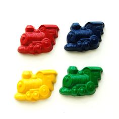 four different colored train shaped magnets on a white surface