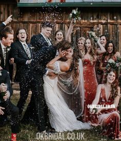 a group of people standing next to each other in front of a wooden building with confetti falling on them