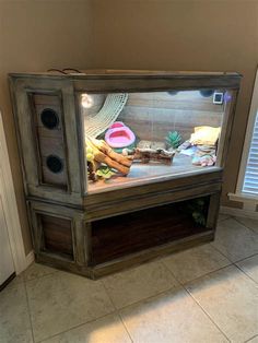 a large fish tank sitting on top of a tiled floor next to a window with shutters