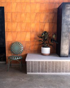 a chair sitting next to a fire place with a potted plant on top of it