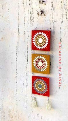 three colorful wall hangings with tassels on the bottom one is red, yellow and white