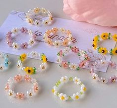 several different types of bracelets on a white surface next to a pink flowery pillow