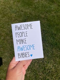 someone holding up a card that says awesome people make awesome babies on the front lawn