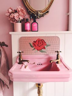 a pink bathroom sink sitting under a mirror next to a wall mounted faucet