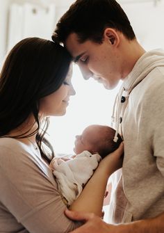 a man and woman holding a baby in their arms