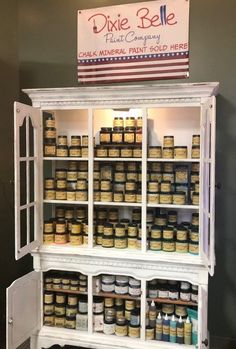 an old white cabinet filled with lots of different types of paint and some signs above it