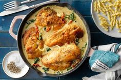 a pan filled with chicken, pasta and spinach on top of a blue table