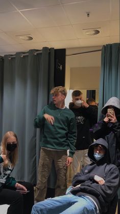 a group of people standing and sitting in front of a mirror with masks covering their faces