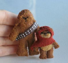 two small stuffed animals are being held in the palm of someone's hand, one is wearing a sweater and the other has a scarf around his neck