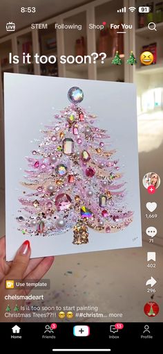 someone holding up a card with a pink christmas tree on it