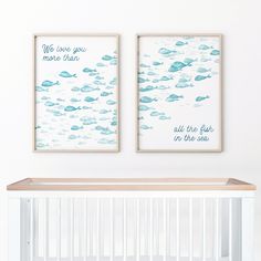 two framed pictures hang above a crib in a baby's room with white walls