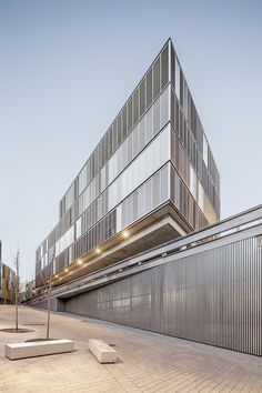 the building has many windows on it's side and is surrounded by concrete blocks