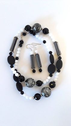 This beautiful black and white necklace set is 24 inch long  and has a 2.5 inch silver extender with a silver clasp. Necklace is made up of lovely onyx beads, white onyx, six black faceted onyx, and six unpolished black oval shaped onyx.  Necklace also has five beautiful glass beads  which  three are round and two barrel shaped . Glass beads are beautifully made  and the main focus of necklace. The matching earrings are made of the glass barrel beads and are sterling silver hooks.   Onyx is believed to have powerful vibrations of  protection and strength. This beautiful black and white necklace is stunning with a black or white dress. It can also complement other color outfits.  Necklace set is placed in a delicate bag and boxed for ready to gift to that special person in your life.  Your Elegant Handmade Black And White Jewelry, Adjustable Black And White Beaded Jewelry, Beaded Black And White Jewelry Gift, Black And White Round Bead Jewelry, Glass Bead Jewelry, Black And White Necklaces, Color Outfits, Glass Beads Jewelry, White Onyx