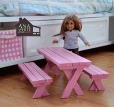 a doll is standing next to a pink picnic table and bench in front of a bed