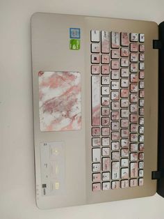 a computer keyboard with pink and white marbled keys on the back cover, attached to a wall