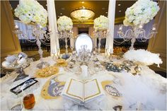 an elaborate table setting with white flowers and chandeliers in the centerpieces