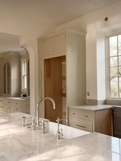 a large kitchen with marble counter tops and white cabinets, along with an island style sink