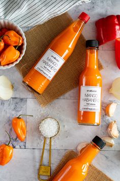 bottles of hot sauce sitting on top of a counter next to garlic and pepper shakers