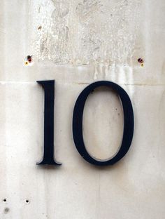 the number ten is written in black on a white wall