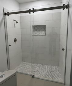 a bathroom with a walk in shower next to a white toilet and tiled flooring