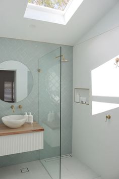 a bathroom with a skylight above the sink and mirror on the wall next to it