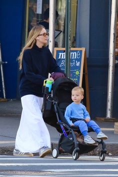 a woman pushing a stroller with a baby in it