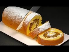 a white plate topped with a roll covered in powdered sugar next to a knife