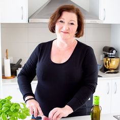 a woman standing in front of a cutting board