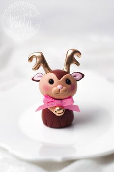 a small figurine on a white plate with a pink bow around its neck