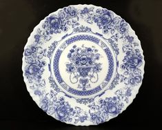 a blue and white plate sitting on top of a black tablecloth covered table next to a wall