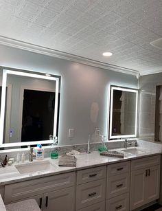 a bathroom with double sinks and mirrors in the middle, along with two lights on either side