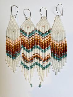 three white and brown beaded earrings hanging from hooks