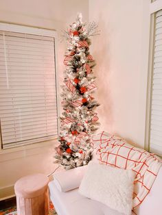 a white christmas tree with red and silver ornaments in the corner of a living room