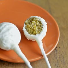 two marshmallows on an orange plate with white icing and crumbs