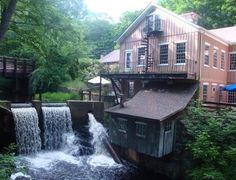 there is a small waterfall coming out of the water in front of a building with a balcony