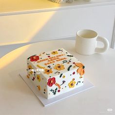 a birthday cake sitting on top of a table next to a cup and saucer