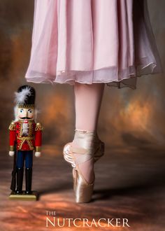 a nutcracker is standing next to a ballerina's foot in ballet shoes