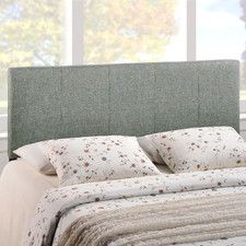 an upholstered headboard on a bed with pillows and blankets in front of a window